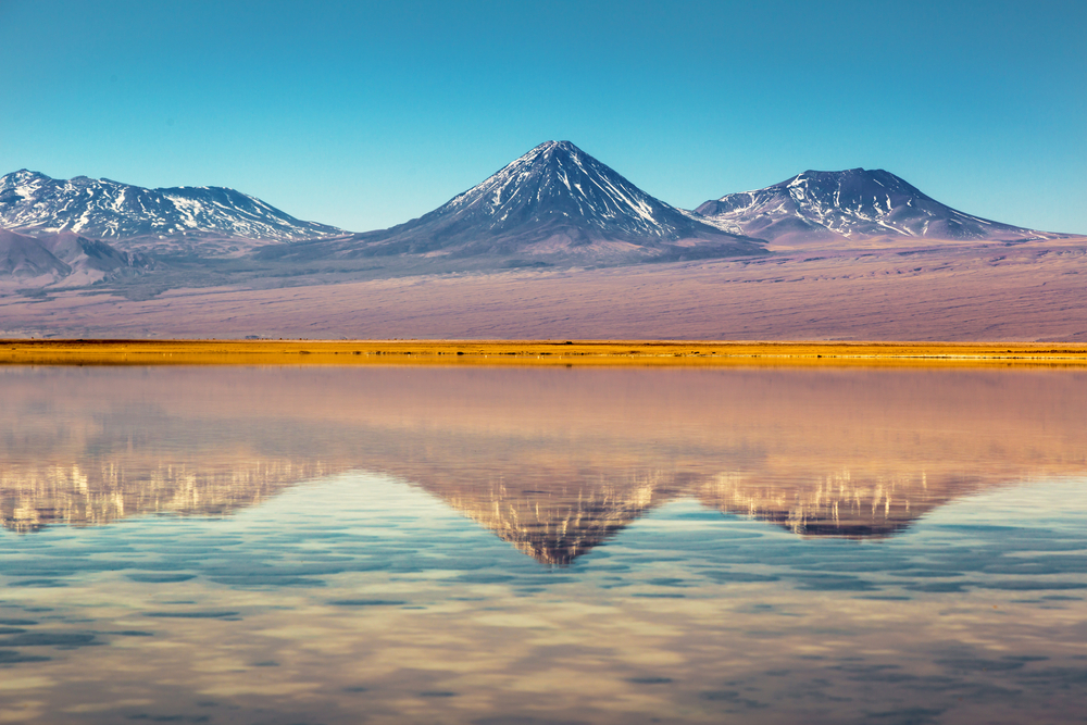 mountains with yellow in front and reflection in water atacama chile