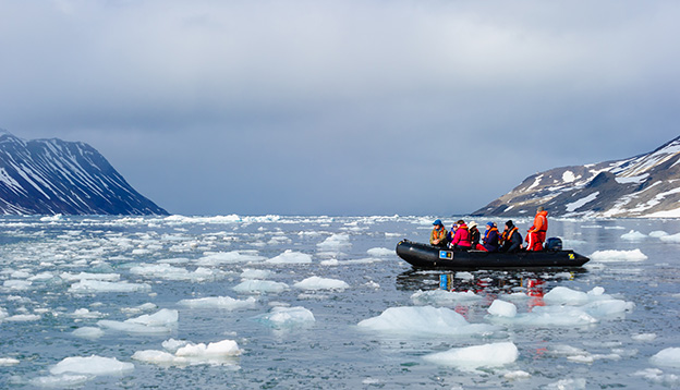 Tourists from the National Geographic Explorer cruise ship explore a fjord in the Arctic via a zodiac