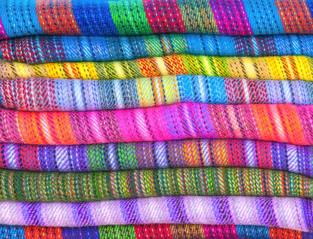 A pile of brightly coloured fabrics of wool lama and alpaca in market Uyuni, Peru, Latin America Credit: Shutter stock