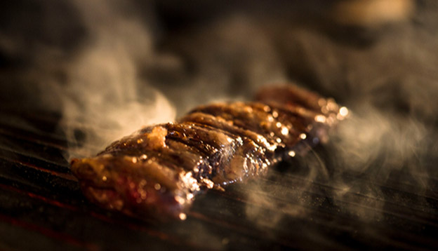 Close up of meat being cooked on a grill - Asado