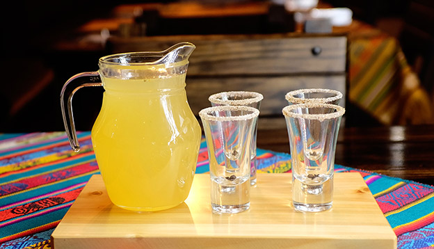 A jug of Canelazo with 4 glasses on a table