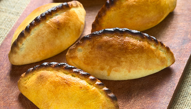 Traditional Bolivian savory pastry called Saltena filled with thick meat stew, which is a popular street snack in Bolivia.