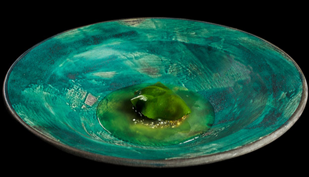 Close up of a dish served on a teal plate set against a black backdrop