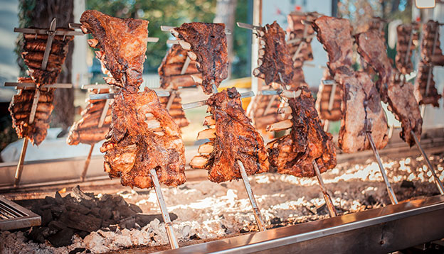 Asado, traditional barbecue dish in Argentina, roasted meat of beef cooked on a vertical grills placed around fire