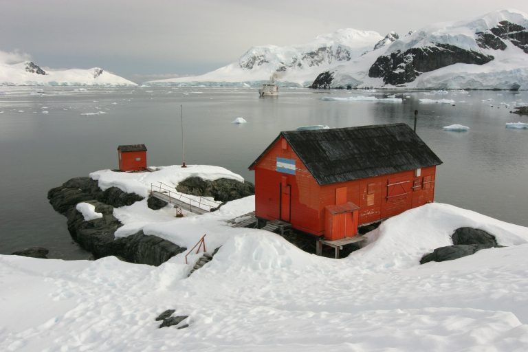 red buiding in the snow on antarctica next to the sea