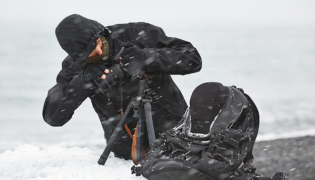 Photographer changing lens in challenging conditions in a snow storm