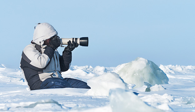 Phtographer photographing with telephoto lens in the Arctic ice